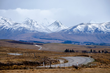 Winter landscape image of winding road leading towards the snow mountain in New Zealand.