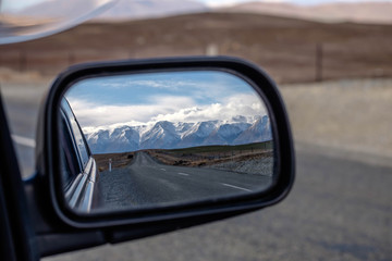 Side view mirror from car travel road trip scenery mountain in New Zealand.