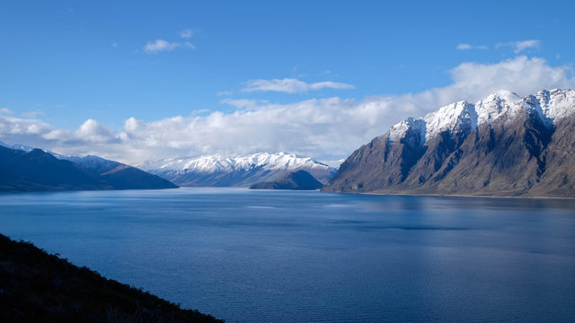 New Zealand travel image of Lake Hawea with snow mountain and blue mirror lake. Peaceful image of natural scenery during winter season in South island, New Zealand.
