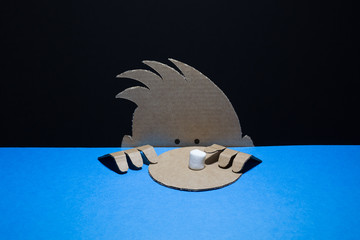 Cute cardboard boy looks at the marshmallow on paper dish. Marshmallow experiment   concept.