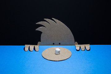 Cute cardboard boy looks at the marshmallow on paper dish. Marshmallow experiment   concept.