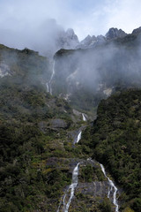 Fototapeta na wymiar In Milford Sound cruise, one experience the spray of a waterfall close to sheer rock faces. A popular tourist destination and natural landscape in New Zealand. This view is breathtaking and iconic.