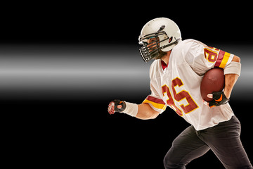 American football player in motion with the ball on a black background with a light line, copy space. The concept of the game is American football, movement.