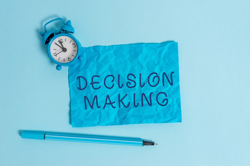 Writing note showing Decision Making. Business concept for The act of deciding between two or more possibilities Metal vintage alarm clock crushed sheet marker sky colored background