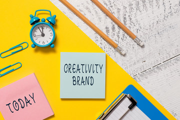 Word writing text Creativity Brand. Business photo showcasing design name or feature that distinguishes organization Notepads clips paper sheet clipboard markers alarm clock wooden background
