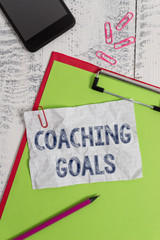 Handwriting text Coaching Goals. Conceptual photo Empowers individuals Encourages them to take responsibility Clipboard paper sheet pencil smartphone note clips wooden retro background