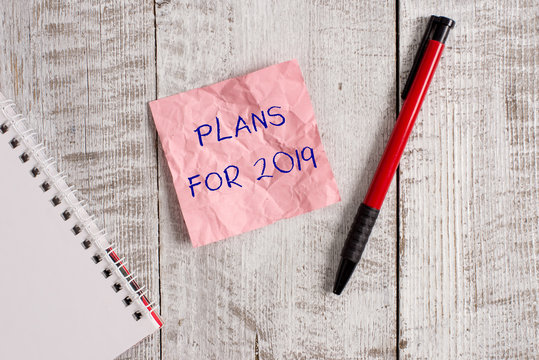Writing note showing Plans For 2019. Business concept for an intention or decision about what one is going to do Wrinkle paper notebook and stationary placed on wooden background