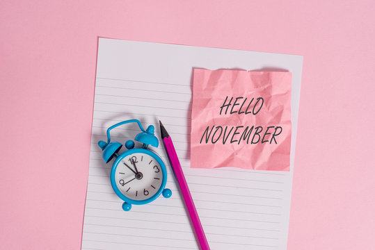 Writing note showing Hello November. Business concept for Welcome the eleventh month of the year Month before December Striped paper sheet note pencil vintage alarm clock colored background