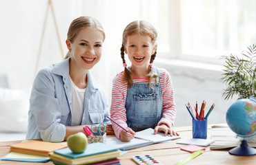 mother and child daughter doing homework writing and reading at home.