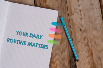Conceptual hand writing showing Your Daily Routine Matters. Concept meaning practice of regularly doing things in fixed order Striped notebook colored arrow banners ballpoint wooden background