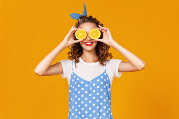 cheerful young curly woman girl with   orange   on  yellow   background.