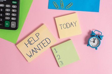 Conceptual hand writing showing Help Wanted. Concept meaning An ad in the paper an employer places to find a new employee Alarm clock calculator notepads paper sheet color background