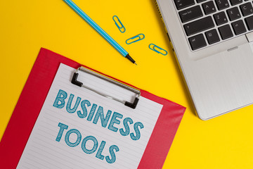 Word writing text Business Tools. Business photo showcasing Marketing Methodologies Processes and Technologies use Open laptop clipboard blank paper sheet marker clips colored background