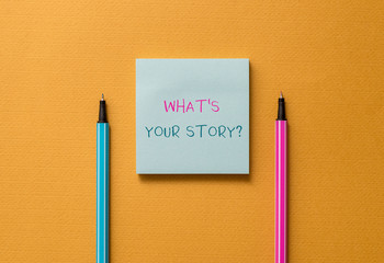 Text sign showing What S Is Your Storyquestion. Business photo showcasing analysisner of asking demonstrating about past life events Front view blank colored sticky note two ballpoints cool yolk