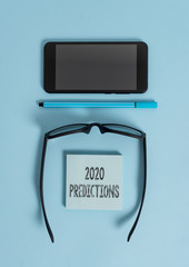 Conceptual hand writing showing 2020 Predictions. Concept meaning list of things you feel that going to happen without proof Dark eyeglasses colored sticky note smartphone pastel background