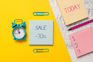Handwriting text writing Sale 30 Percent. Conceptual photo A promo price of an item at 30 percent markdown Notepads clips colored paper sheet marker alarm clock wooden background