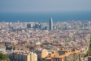Obraz premium Barcelona, Spain - April, 2019: View of Barcelona city and costline in spring from the Bunkers in Carmel neighborhood. Few building stand out like sagrada familia and Agbar tower