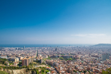 Fototapeta na wymiar Barcelona, Spain - April, 2019: View of Barcelona city and costline in spring from the Bunkers in Carmel neighborhood. Few building stand out like sagrada familia and Agbar tower