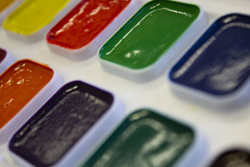 Multicolored watercolor paint in white box