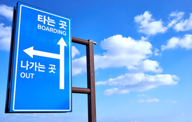 A sign post guiding directions written 타는 곳(boarding) and 나가는 곳(out).