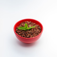 Red quinoa cooked in red bowl on white background