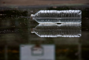 A water bottle with its reflection and basketball hoop in background
