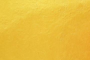Gold paint on rough cement wall texture.