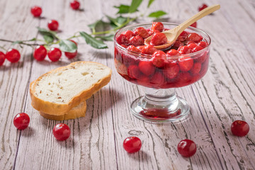 Pieces of bread next to a bowl filled with cherry jam. Homemade jam from the fresh harvest of cherry berries. Flat lay.