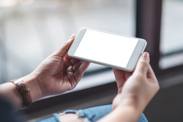 Mockup image of a woman holding white mobile phone with blank desktop screen in cafe