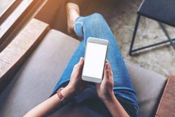 Top view mockup image of woman holding white mobile phone with blank screen while sitting in cafe