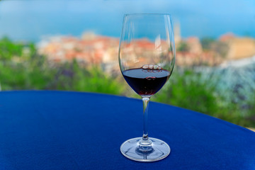 Glass of local red wine on the table at a restaurant with Budva Old Town and Adriatic Sea in Montenegro in background