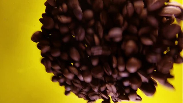 Slow Motion Of Mixing Coffee Beans In A Glass Isolated On Yellow Bacground.
