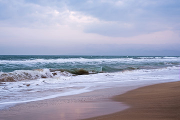 Beach at sunset or sunrise. Sandy beach with sea waves at sunset