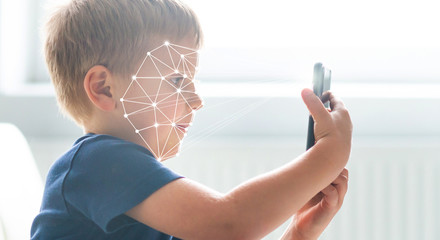 Kid using face id recognition. Boy with a smartphone gadget. Digital native children concept.