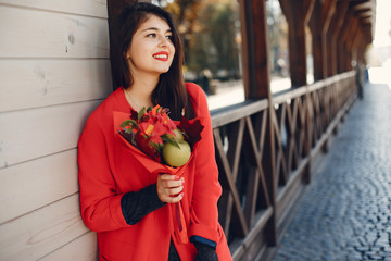 Beautiful girl in a city. Stylish girl in a fashionable clothes. Lady with a unordinary bouquet