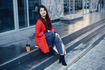 Fototapeta premium Beautiful girl in a city. Stylish girl in a fashionable clothes. Lady standing near gray building.
