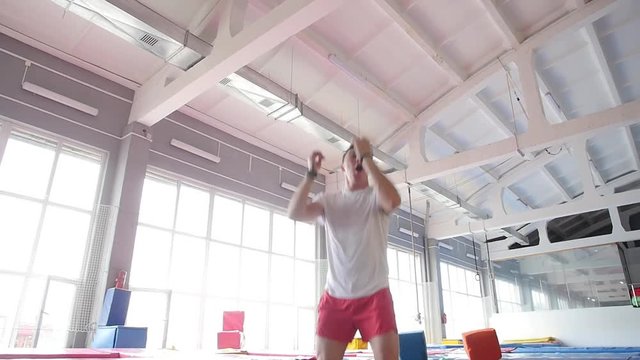 Fitness and entertainment concept. A young fit happy man jumping and flying on trampoline