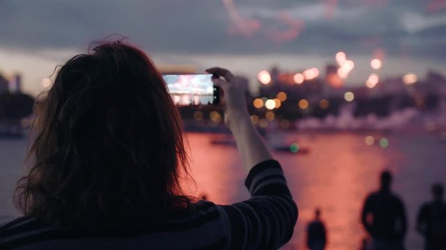 Women taking pictures of Fireworks Display. video and photo technology crowd holidays memories 4k. Beautiful moving particles background and glitter USA 4th of July New Year Celebration