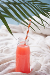 Refreshing summer tropical cocktail in a bottle with straw on a gray concrete background. Drink detox.