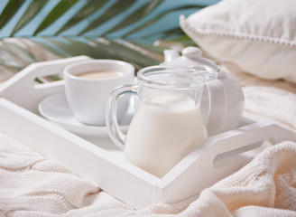 Close up of cup of tea, milk, teapot on the white tray.