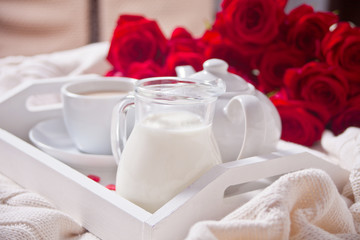 Close up of cup of tea with red roses on the white tray