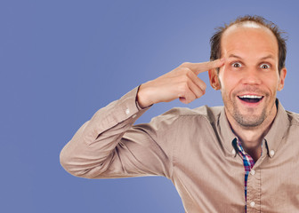young man gesturing with his finger against his temple. on blue color background