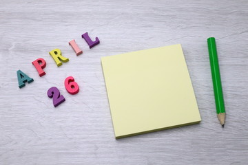 April 26 - Daily colorful Calendar with Block Notes and Pencil on wood table background, empty space for your text or design