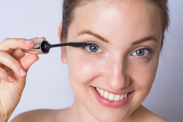 Fototapeta premium Young woman applying black mascara.