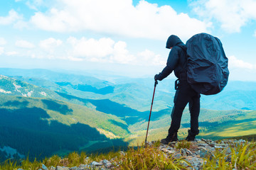 A man rises in the mountains with walking sticks.