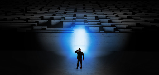 Businessman getting ready to enter the dark labyrinth with illuminated door