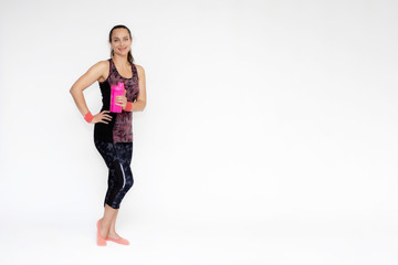 Full-length portrait on white background of beautiful pretty fitness girl woman in pink sports uniform, stands exercising in various poses with a shaker. Smiles Stylish trendy youth.