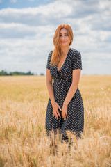 Elegant woman in long black polka dot dress at the field 