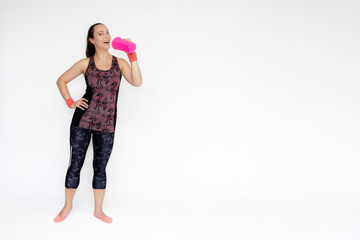 Full-length portrait on white background of beautiful pretty fitness girl woman in pink sports uniform, stands exercising in various poses with a shaker. Smiles Stylish trendy youth.