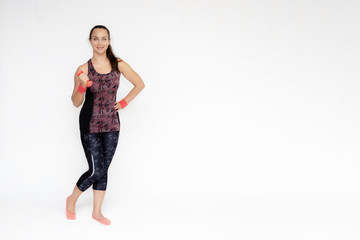 Full-length portrait on white background of beautiful pretty fitness woman girl in fashionable sportswear standing exercising in various poses with dumbbell. Smiles Stylish trendy youth.
